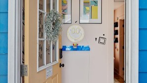 A door with a checkered floor, a wall with framed pictures, and a small shelf with items.