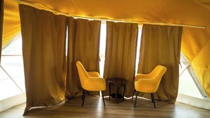 Una habitación con techo alto y tejado inclinado, que incluye dos sillas amarillas y una pequeña mesa redonda.
