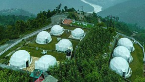 Varias estructuras en forma de cúpula en una zona montañosa y exuberante, con un río al fondo.