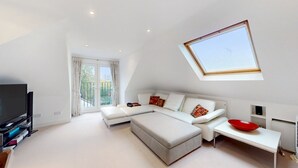 A modern living room with a large sofa, a TV, and a skylight. - Charming house in Golders Green - Pass the Keys (London)