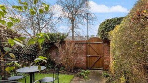 A patio area with a brick wall, a wooden gate, and a small lawn.