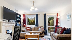 A cozy living room with a fireplace, a flat-screen TV, and a comfortable seating area with two sofas and a coffee table.