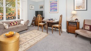 A living room with a sofa, a dining table with chairs, a TV, and a rug. - Brockley Victorian apartment train links London - Pass the Keys (London)