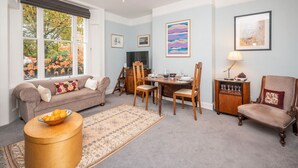 A living room with a sofa, a dining table with chairs, a TV, and artwork on the walls. - Brockley Victorian apartment train links London - Pass the Keys (London)