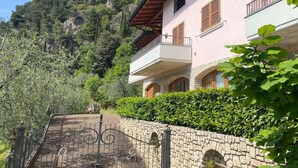 Un edificio de dos pisos con un muro de piedra y una reja de hierro forjado.