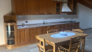 Una cocina con armarios de madera, un fregadero y una mesa de comedor con sillas.