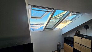 Ein Zimmer mit Oberlichter, Heizkörper und einem Holzkasten.