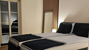Ein Schlafzimmer mit Bett, Kleiderschrank, Spiegel und Deckenleuchte.