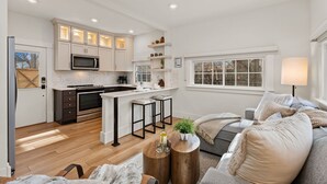 A modern kitchen with a central island, bar stools, and a dining area with a sofa and coffee table. - Chic Luxury Retreat – Old Town Carriage House (Fort Collins)