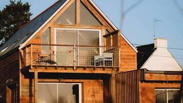 A wooden house with a balcony, large windows, and a garage.