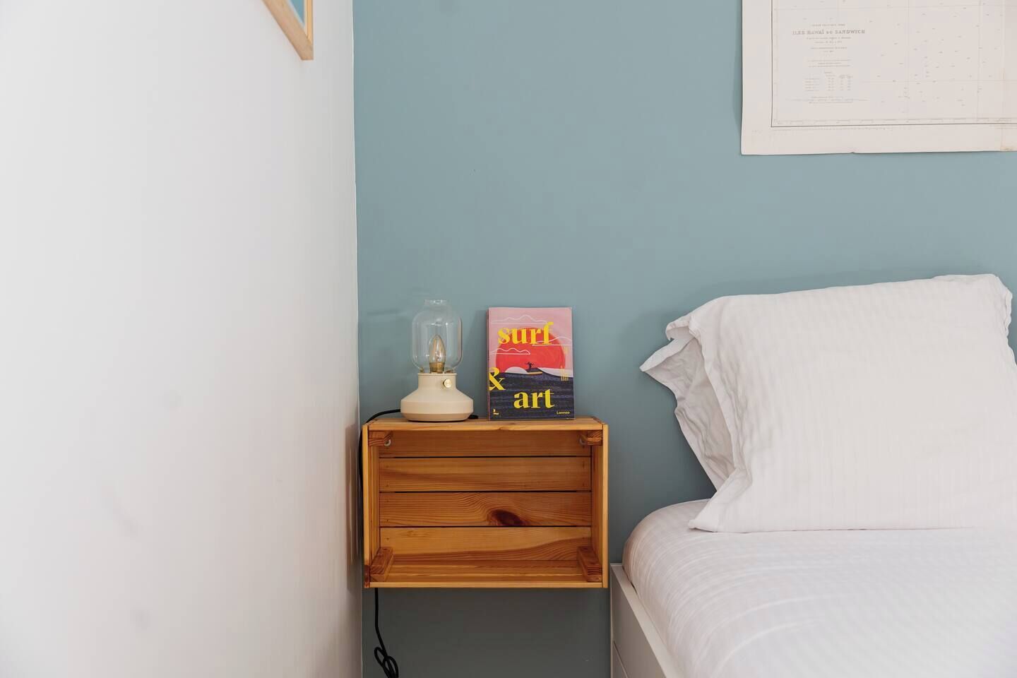 Una camera da letto con un letto singolo, un comodino con una lampada e un quadro appeso al muro.