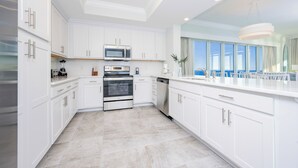 A modern kitchen with white cabinetry, stainless steel appliances, and a large window providing natural light.
