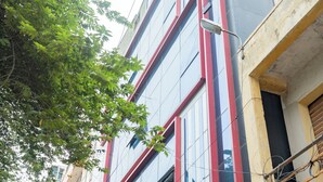 A multi-story building with commercial signage, including a travel agency and insurance services. - VJ Rooms (Bengaluru)