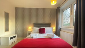 A hotel room with a large bed, two bedside lamps, a window with curtains, and a radiator. - Spacious 2 Bedroom flat with Balcony – 5 min to Kennington Tube, Central London (London)