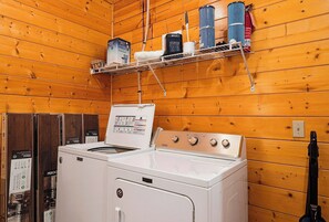 A laundry room with a white washing machine, a dryer, and a shelf with cleaning supplies.