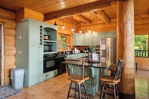 A cabin-style kitchen with a central island, wooden cabinets, and a built-in oven.