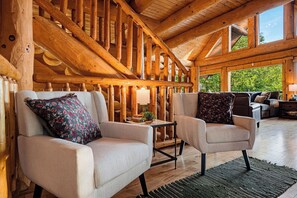 A log cabin interior with two armchairs, a small table, and a sofa. - Round Log Cabin with Stunning Views (Gatlinburg)