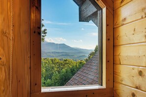 A wooden cabin with a window revealing a mountainous landscape. - Round Log Cabin with Stunning Views (Gatlinburg)