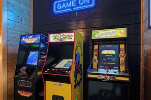 Three arcade machines with neon signs, one labeled 'GAME ON' and others featuring 'Pac-Man' and 'Dig Dug'.