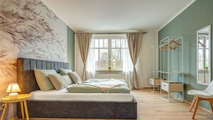 Une chambre moderne avec un grand lit, une table de chevet avec une lampe, une armoire et un miroir.