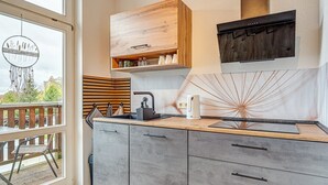 Une cuisine moderne avec des meubles gris, un plan de travail en bois et une cuisinière intégrée.