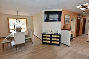 Relax in this serene living area with a dining table for two, a comfortable chair, and a flat-screen TV.