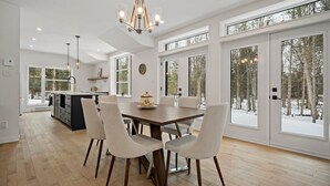 A modern kitchen with a dining area, large windows, and a chandelier. - 1 month for the price of 1 week! (Mont-Tremblant)