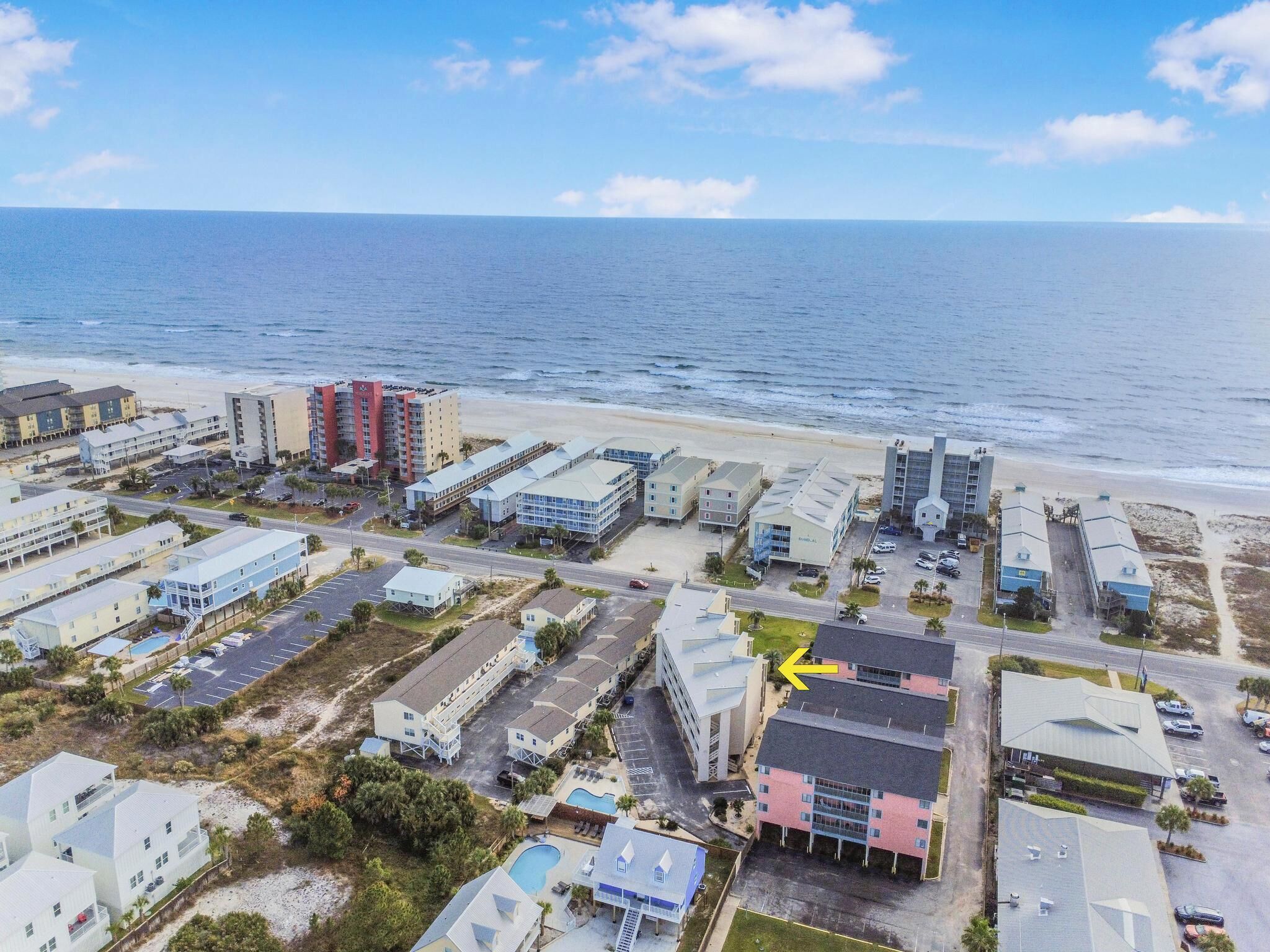 Vista aérea de uma área costeira com um hotel e vários edifícios, uma praia e o oceano.