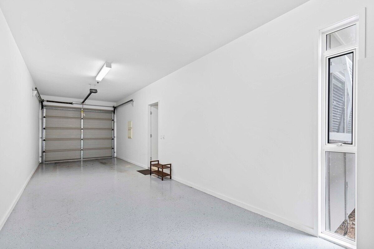 Ein Flur mit einer Garagentür, einem kleinen Tisch und einer Tür zu einem Zimmer.