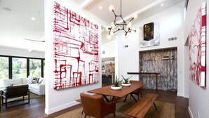 Un comedor moderno con una mesa de madera, bancos y un cuadro abstracto grande en tonos rojo y blanco.