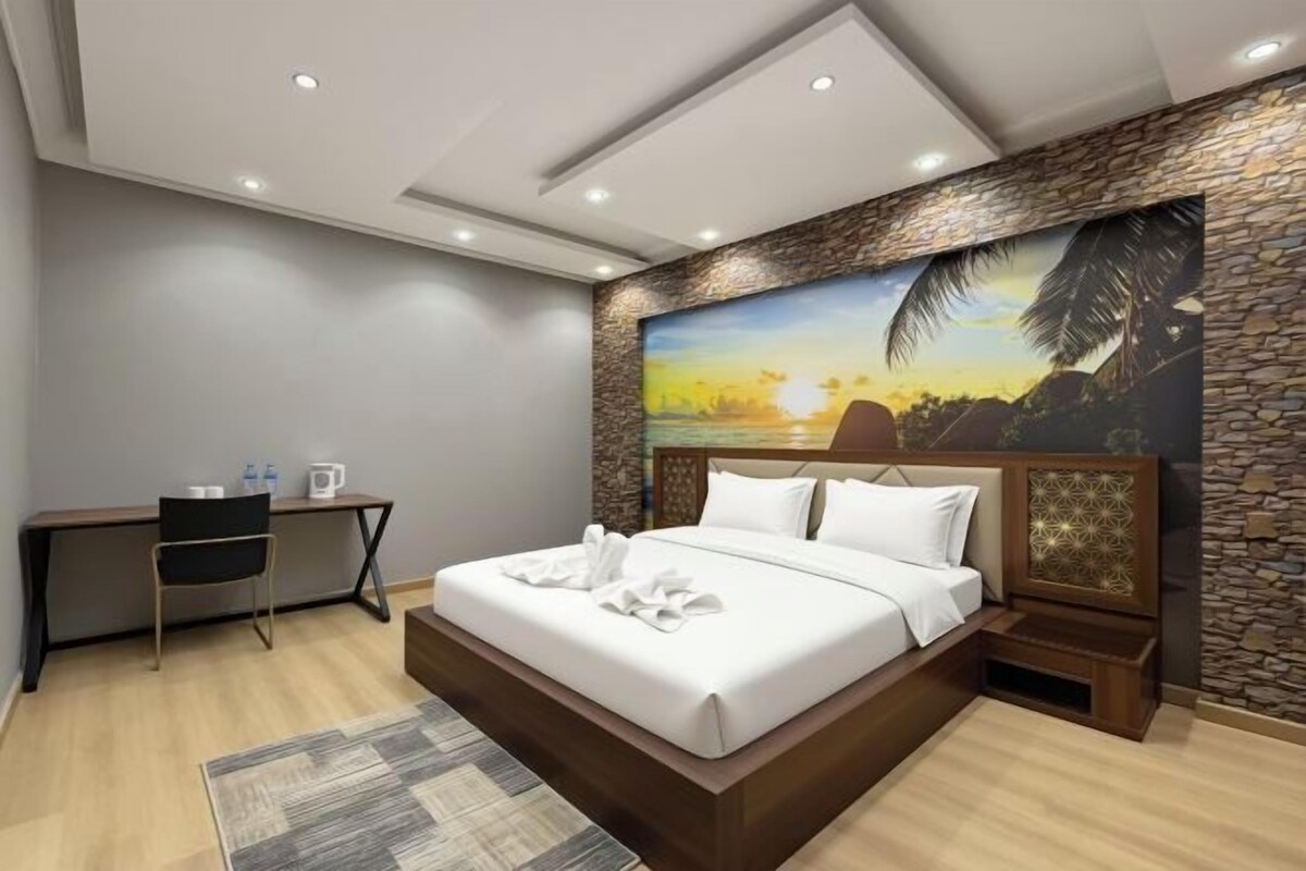 Una habitación de hotel moderna con una cama grande, un escritorio y un mural en la pared.