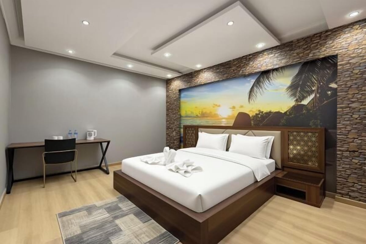 Ein modernes Hotelzimmer mit einem großen Bett, einem Schreibtisch und einem Wandgemälde.