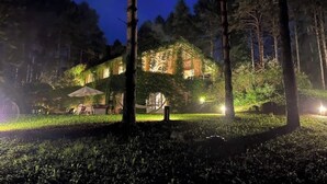 Un edificio de diseño rústico, rodeado de árboles e iluminado con luz artificial.