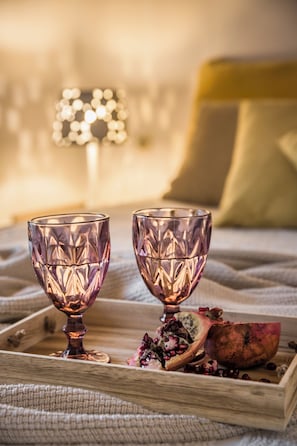 Two glass goblets on a wooden tray with a pomegranate and decorative elements.