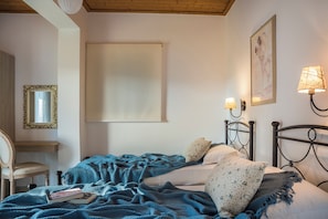 A bedroom with a bed, a chair, a mirror, and a wall-mounted lamp.