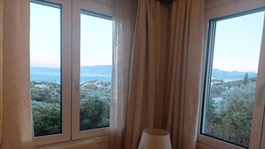 A room with two windows offering a view of a coastal landscape. - Sunny apartment with view to the Mirabello Gulf (Agios Nikolaos)