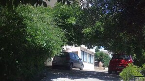 A narrow street with parked cars and lush greenery on both sides. - Sunny apartment with view to the Mirabello Gulf (Agios Nikolaos)
