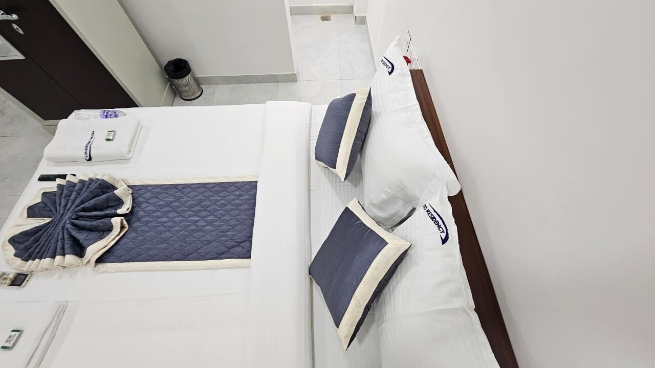 A neatly made bed with a quilted blanket, pillows, and a folded blanket on the side.