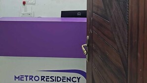 Una zona de recepción con un mostrador morado, una computadora Dell y un cartel que dice "METRO RESIDENCY".
