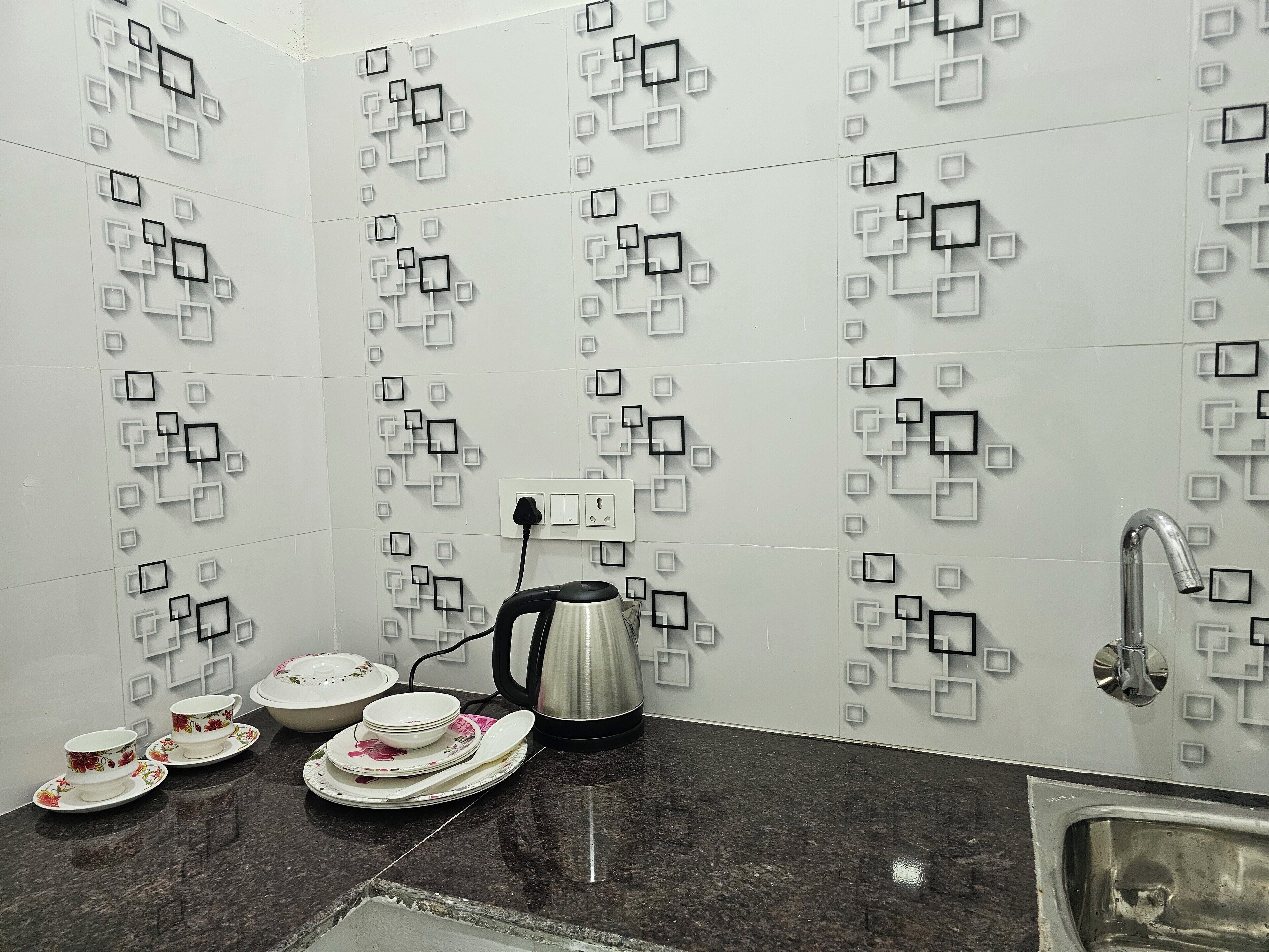 A kitchen with white tiled walls, a black countertop, and a stainless steel sink.