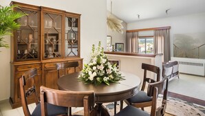 Ein Essbereich mit einem runden Tisch, Holzkstühlen, einer Vitrine mit Glastür und einer Blumenarrangements.