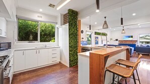 Une cuisine moderne avec des meubles blancs, un îlot central en bois et une grande fenêtre.