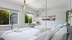 Une chambre moderne avec deux lits, une grande fenêtre et une vue sur la verdure.