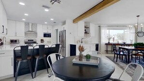 Eine moderne Küche mit weißen Schränken, einem Essbereich mit rundem Tisch und einem großen Fenster für natürliches Licht.