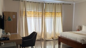 Une chambre d’hôtel avec un lit, un bureau avec une lampe, une chaise et un réfrigérateur.