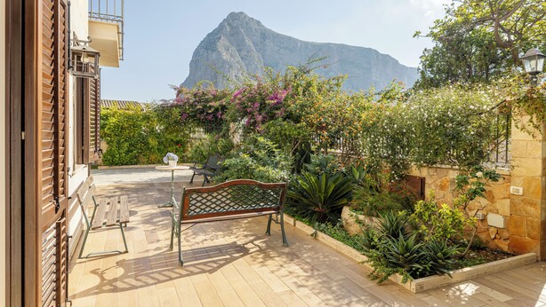 Un patio con un banco de madera, una mesa y una planta en maceta.