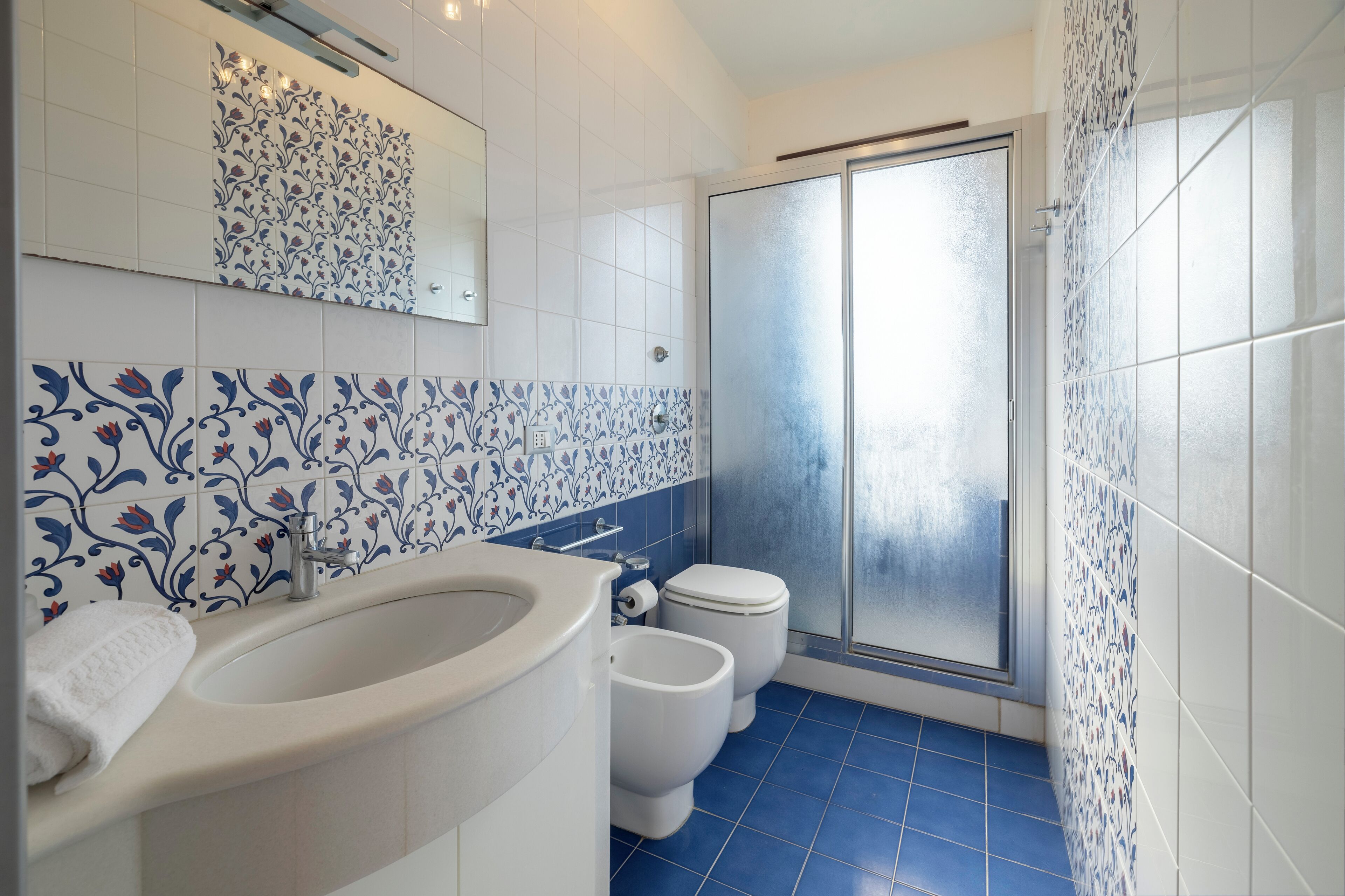 Un bagno con un lavandino bianco, due servizi igienici e una zona doccia.