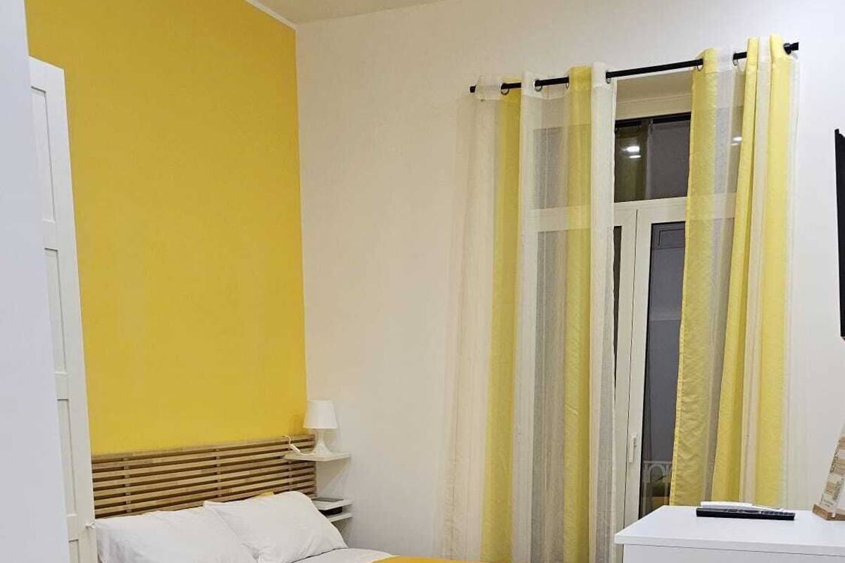 A room with two beds, a small table, and a window with curtains.