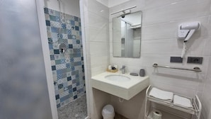 A bathroom with a shower, a sink, a mirror, a hairdryer, and a towel rack. - Appartamento Annunziata (Naples)