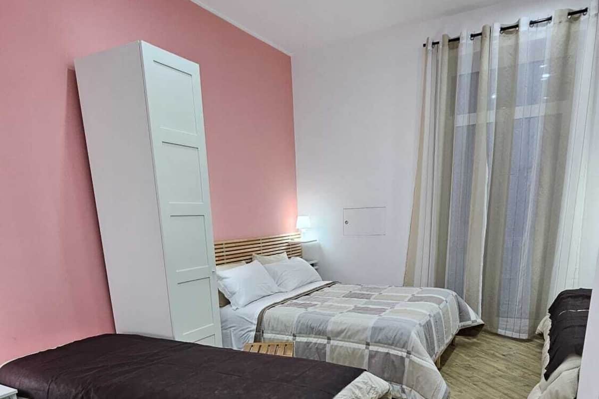 A compact bedroom with two beds, a wardrobe, and a desk.